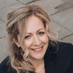 A white woman with blonde hair smiling to the camera.